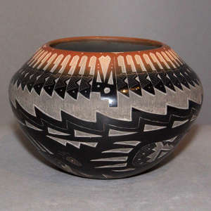 Sgraffito feather, bear paw and geometric design on a black pot with a sienna rim