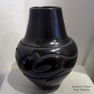 An avanyu and geometric design carved into a black jar