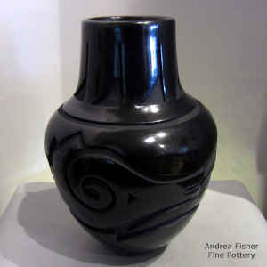 An avanyu and geometric design carved into a black jar