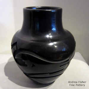 An avanyu and geometric design carved into a black jar