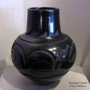 An avanyu and geometric design carved into a black jar