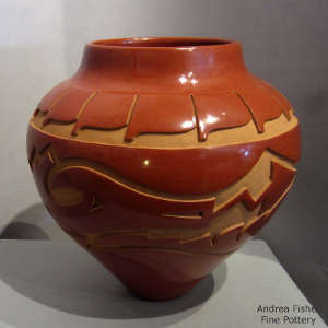 Avanyu and feather design carved into a red jar