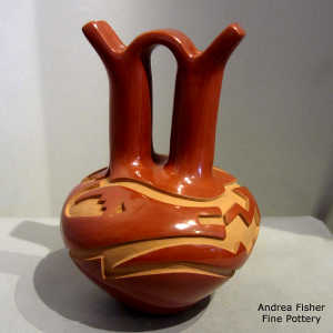 An avanyu and geometric design carved into a red wedding vase