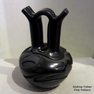 An avanyu and geometric design carved into a black wedding vase