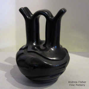 An avanyu and geometric design carved into a black wedding vase