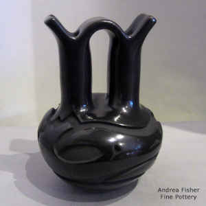 An avanyu and geometric design carved into a black wedding vase