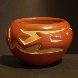 An avanyu design carved into a red jar
