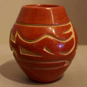 An avanyu design carved into a red jar