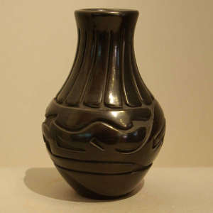 Feather and avanyu design carved into a polished black jar