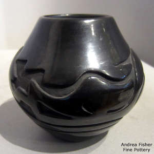 An avanyu design carved into a black jar