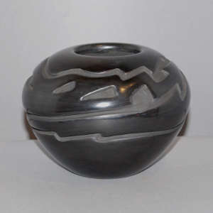 An avanyu design carved into a black jar