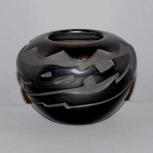 An avanyu and cloud design carved into a black jar