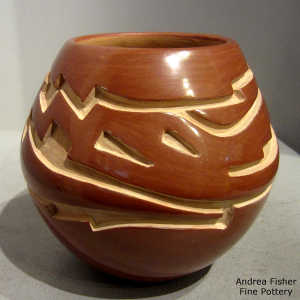 An avanyu design carved into a red jar