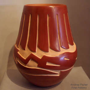 Avanyu and feather design carved into a polished red jar
