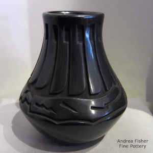 A feather and avanyu design carved into a black jar