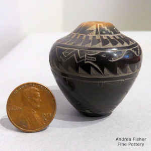 A sgraffito avanyu, mountain lion, deer, feather and geometric design on a miniature black jar with a sienna rim