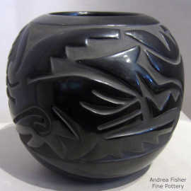 A stylized avanyu and feather design carved into a black jar