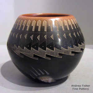Sgraffito bear paws, feathers and geometric design on a black jar with a sienna rim and spots
