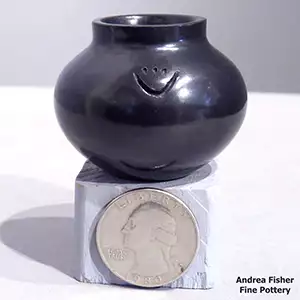 Miniature black jar with bear paw imprints on its body
