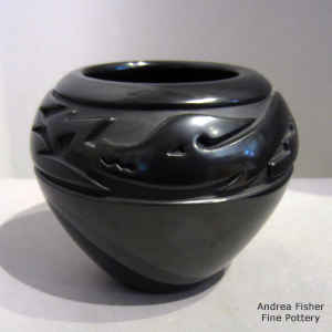 An avanyu design carved around the shoulder of a black jar