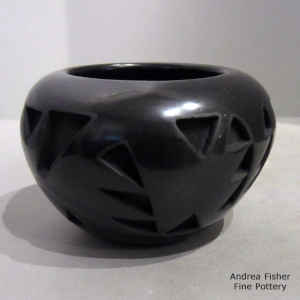 A stylized avanyu design carved into a black jar