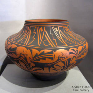 Deer, heart line and geometric designs decorate a black on orange jar