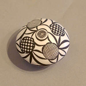 A medallion, checkerboard and geometric design on a black and white seed pot