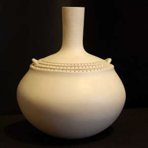 A band of corrugated detail around the upper shoulder of a tall-necked white jar