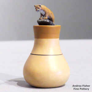 A mountain lion stands on the lid of a miniature polychrome jar with a bear paw design