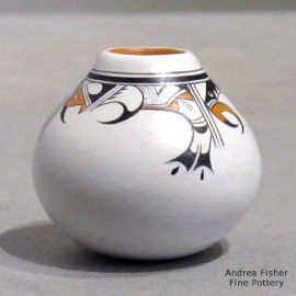A band of bird element and geometric design wrap around the opening of a miniature polychrome jar