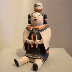 Storyteller with pot on head and holding two ears of corn