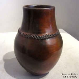 A rope biyo' hangs around the neck of a brown jar with fire clouds