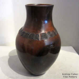 A band of corrugated geometric design on the shoulder of a brown jar with fire clouds