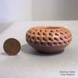 A miniature red jar is corrugated above the shoulder