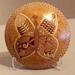 Geometric and stylized butterfly design on a yellow ware seed pot
