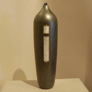 Two sterling silver inlays on a tall black micaceous jar with an organic opening