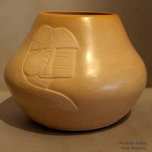 Lightly carved Pueblo face blowing the Breath of Life on a buff-colored jar