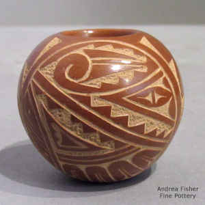 A sgraffito geometric design on a miniature red jar
