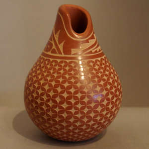 Sgraffito geometric design on a red jar with an oval opening