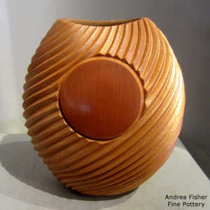 A polished red medallion on a golden micaceous swirl-cut oval piece