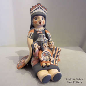 Three children on a grandmother storyteller wearing a manta and tablito