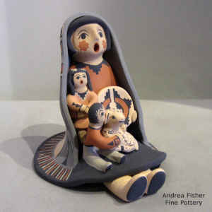 2 children on a grandmother storyteller wearing a manta