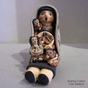 3 children, a pot and a welcome basket on a grandmother storyteller who is wearing a manta