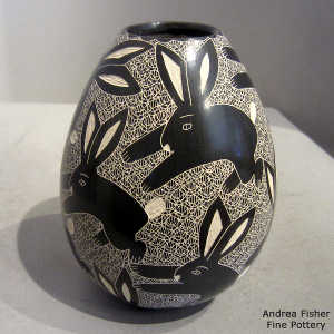 Sgraffito rabbit and mesh design on a black and white jar