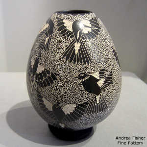 Sgraffito bird and mesh design on a black and white jar