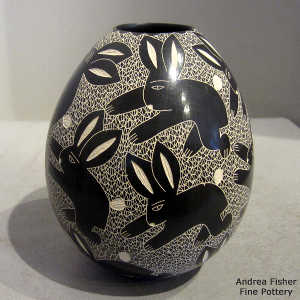 Sgraffito rabbit and mesh design on a black and white jar