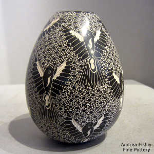 Sgraffito bird and mesh design on a black and white jar