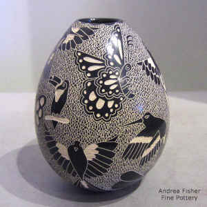 Sgraffito bird, butterfly and mesh motif on a black and white jar