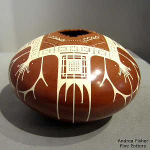 Sgraffito and painted geometric design on a white on red jar with a geometric cut opening
