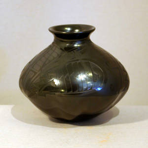 Melon bottom and Paquime designs on the upper half of a black on black jar